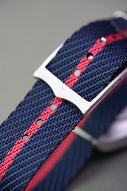 Macro view of brushed steel buckle and punch holes on navy and red woven nylon strap fitted to a Tudor Black Bay
