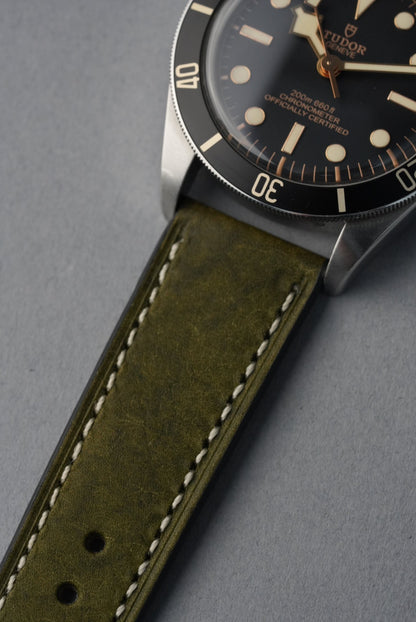 Watch with green leather strap on a gray background