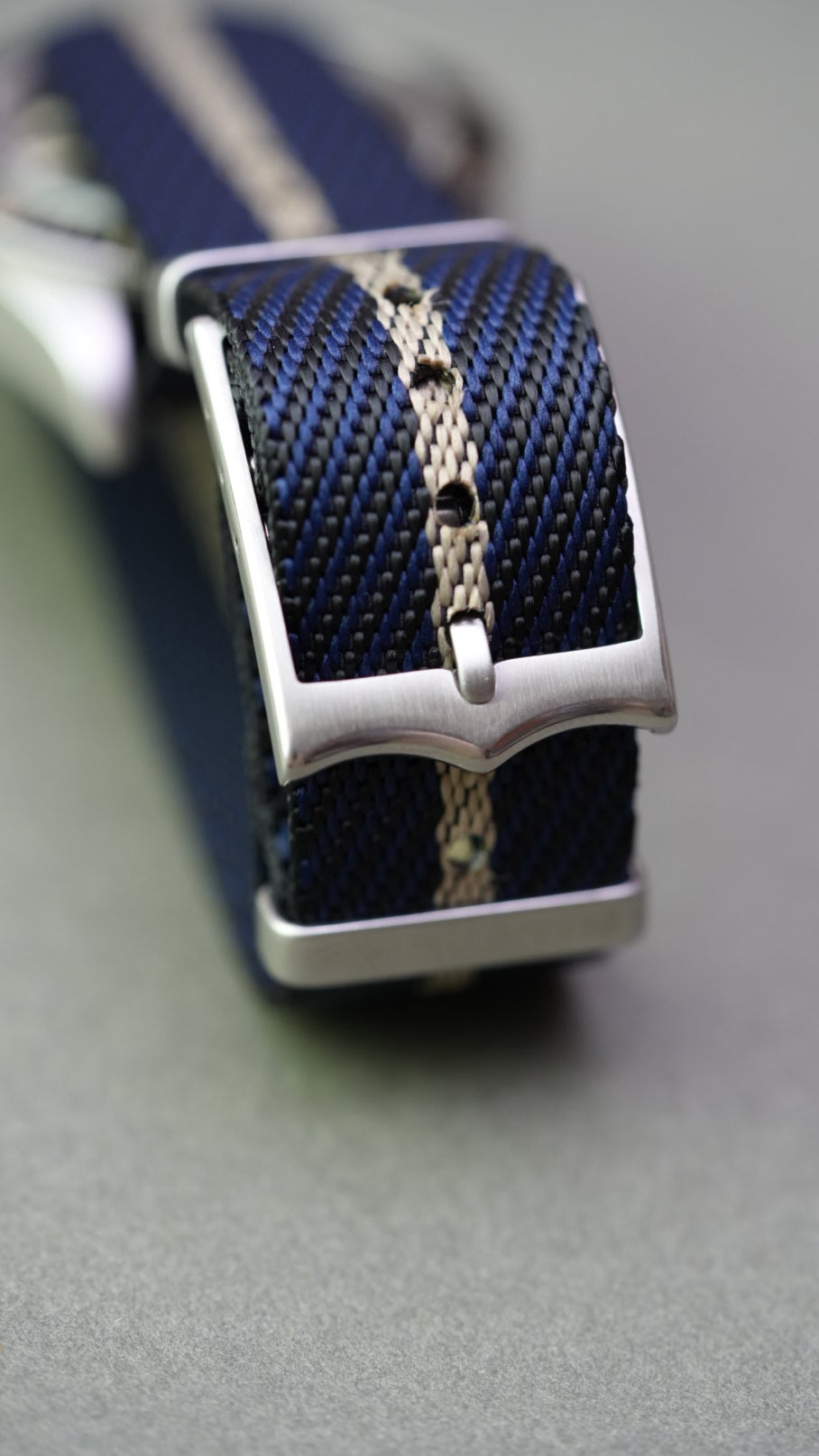 Macro view of woven texture showing black, blue, and cream stripe detail on nylon strap fitted to Tudor Black Bay.