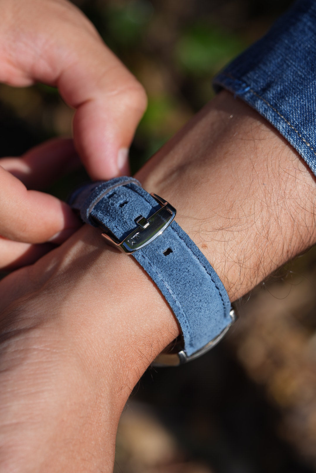 Close-up of blue suede leather watch strap buckle on wrist, paired with Tudor Black Bay