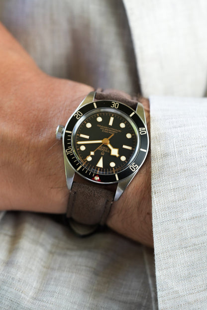 Tudor watch with brown suede strap shown on wrist, paired with light beige shirt