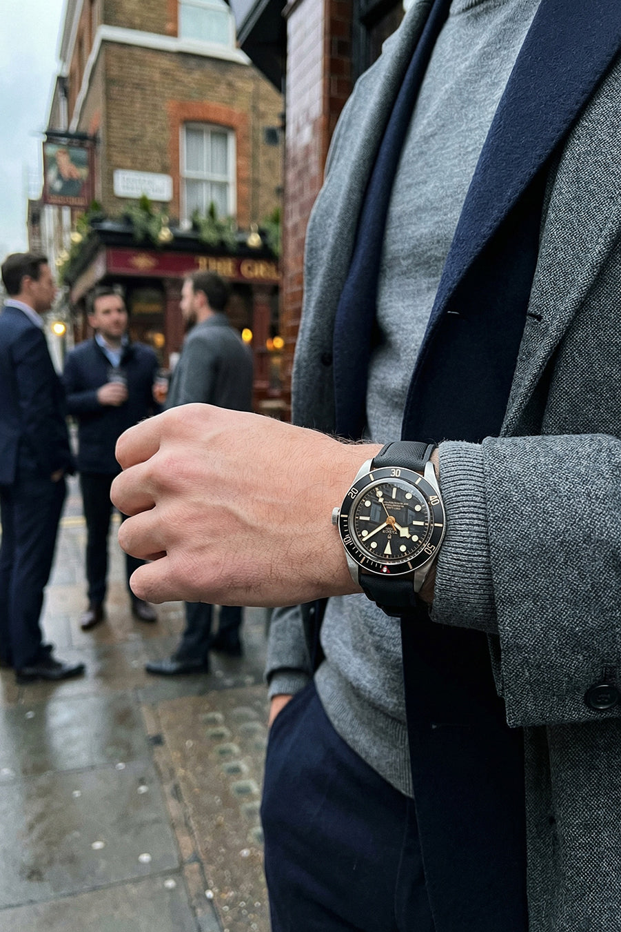 Person wearing a watch with a blurred street scene in the background