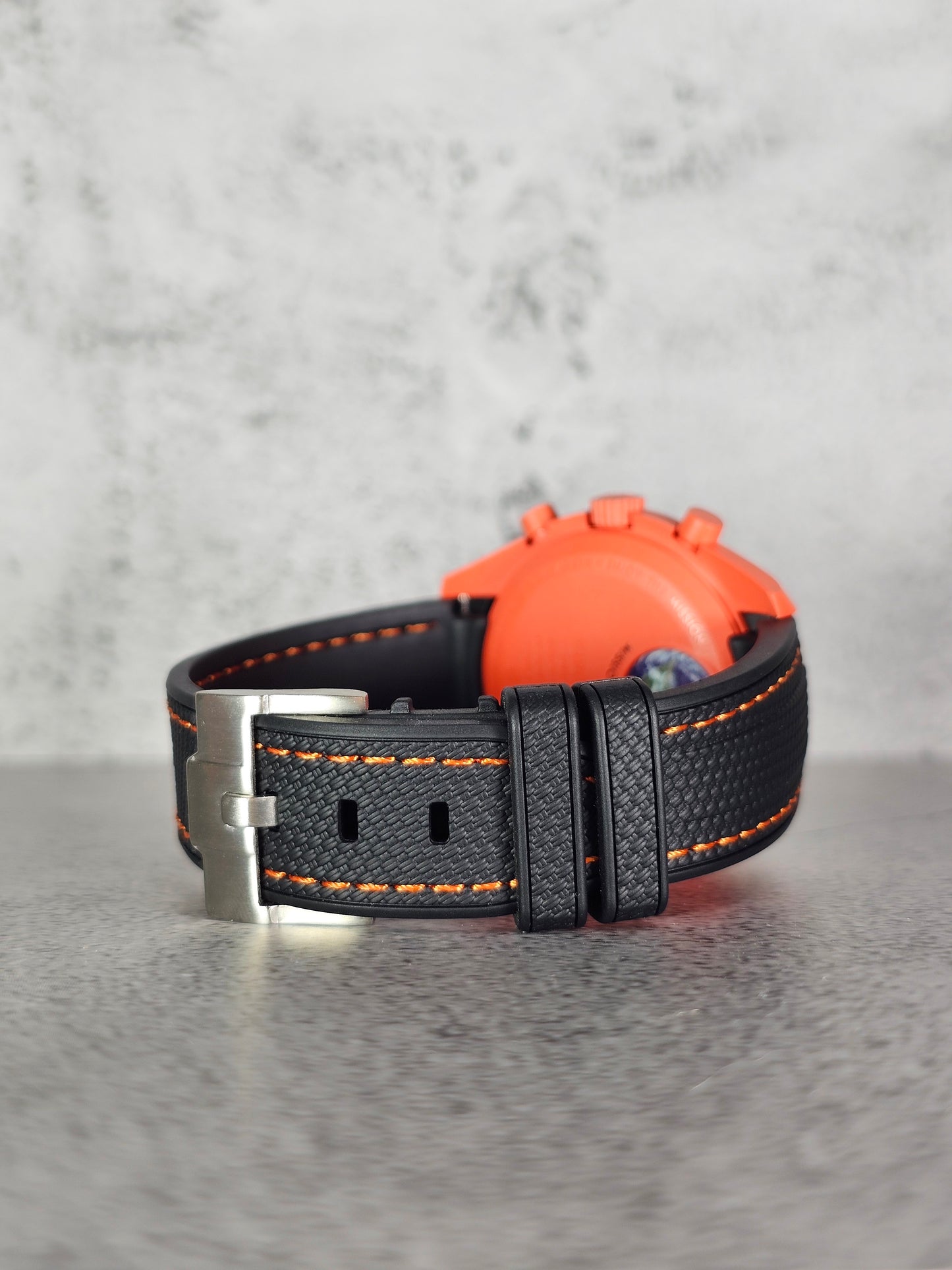 Close-up of woven texture and lava stitching on black rubber MoonSwatch strap for Omega x Swatch Mission on Earth Lava.